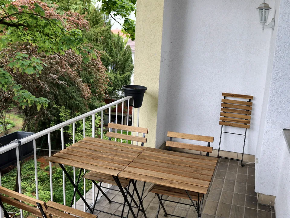 Der Balkon mit Holztischen und Blick ins Grüne